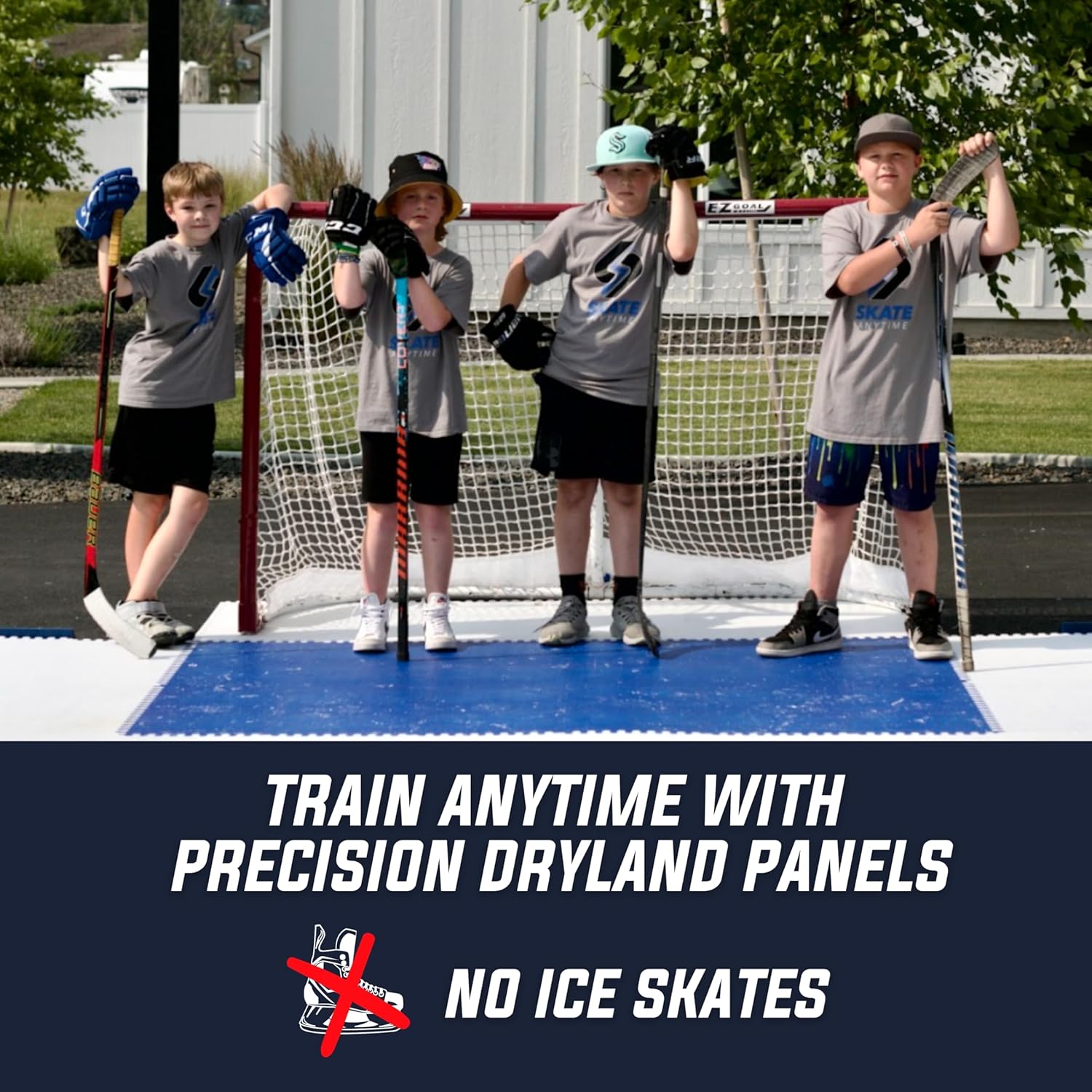Four children wearing gray Pinnacle Dryland training shirts and black shorts stand on an ice rink in front of a hockey goal, holding practice sticks. A dark navy banner at the bottom reads 'TRAIN ANYTIME WITH PRECISION DRYLAND PANELS NO ICE SKATES' with a red X over an ice skate icon.